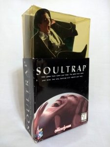 The packaging for SoulTrap. The front of the box has an illustration of a man, either laughing or screaming, trapped in a sphere and pushing his hands against the inside. On top of the box, there is a three-dimensional cutout of another man in a suit screaming; he is trapped in a yellow-tinted plastic enclosure.