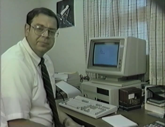 John Hiles demonstrates Entryway, a software platform by Delta Logic. Hiles is sitting in front of an old computer with an assortment of floppy disks on the desk.