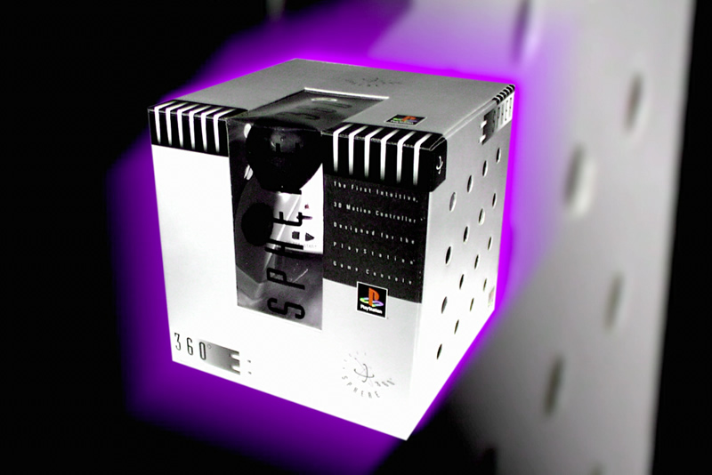 The box for the Asciiware Sphere 360 PlayStation controller. The controller itself is barely visible. The box is a bizarre steel-colored cube with air holes in the side, giving it an industrial appearance. In the picture, the box is glowing purple. 