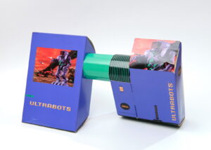 The box for Ultrabots, transformed. The two halves of the box have been separated, connected by a green-and-black-striped axle, and twisted in opposite directions.